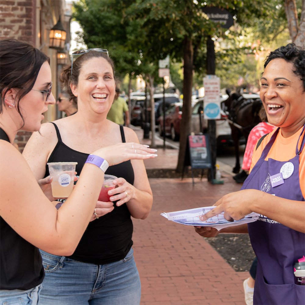 Friends enjoying Sip and Stroll and talking to a First Friday volunteer
